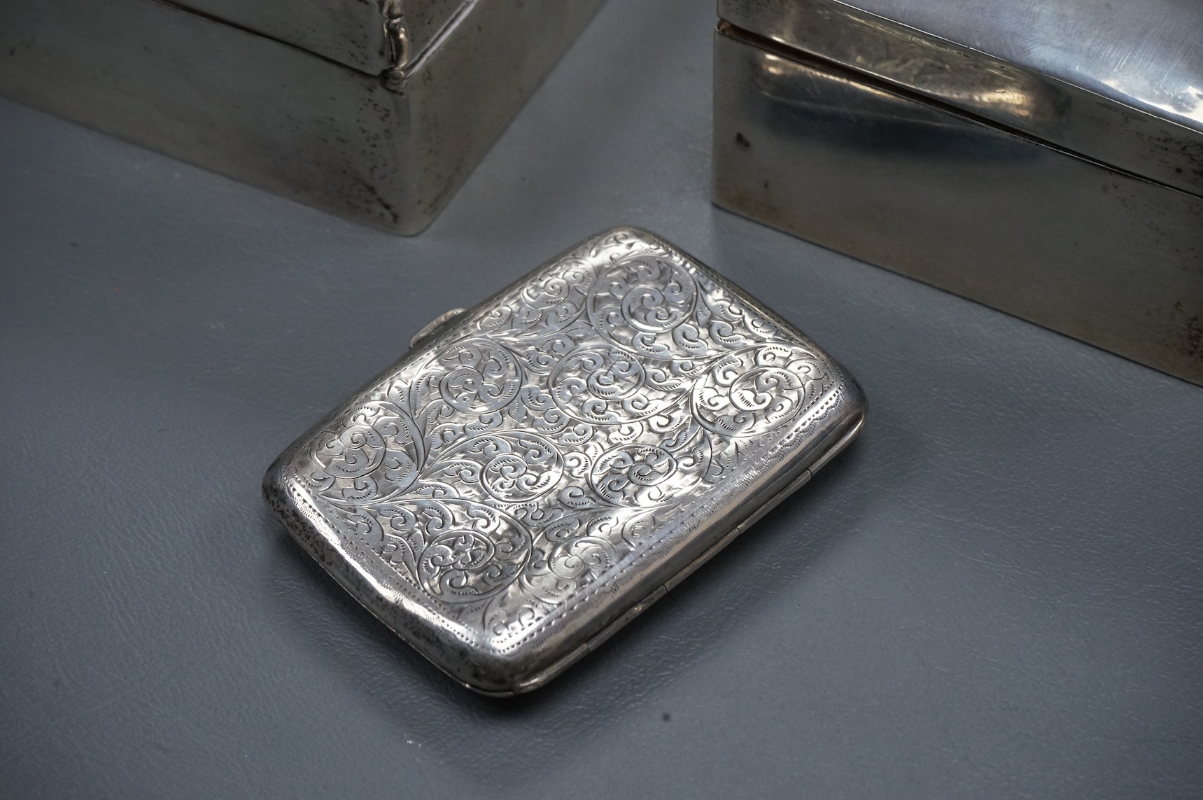 A George V silver mounted rectangular cigarette box, London, 1924, width 16cm, together with a smaller silver mounted cigarette box and a silver cigarette case.